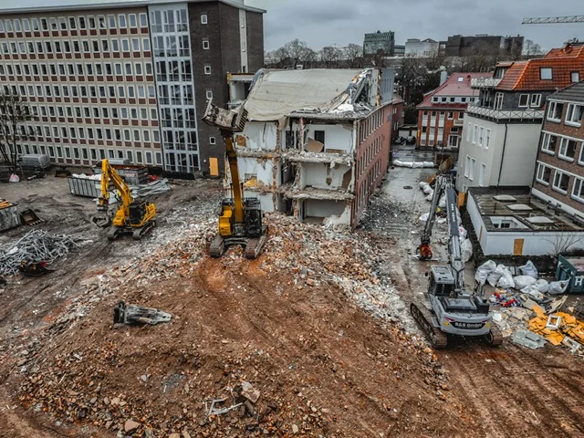 Bagger beim Gebäuderückbau in bebauter Umgebung